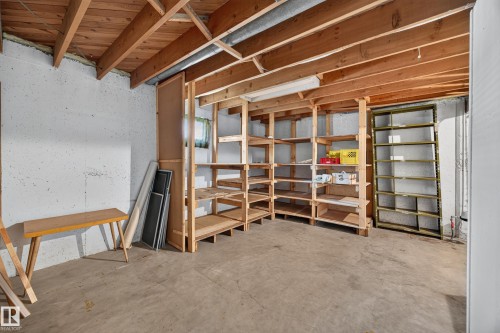 Exposed wood ceiling beams, concrete flooring, and extensive built-in wooden shelving for storage - 5207 48 Avenue, Leduc, AB - Indoor Photo Showing Other Room