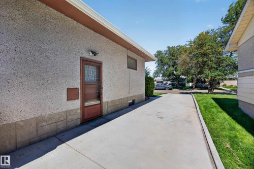 Concrete driveway, stucco exterior, side entry door, exterior lighting, mature trees - 5207 48 Avenue, Leduc, AB - Outdoor With Exterior