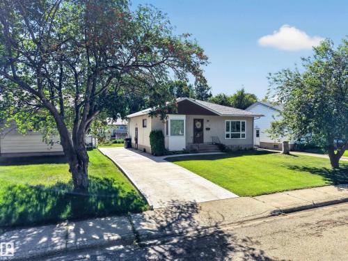 Exterior featuring a front lawn, mature trees, a concrete driveway, and a concrete pathway to the entrance - 5207 48 Avenue, Leduc, AB - Outdoor