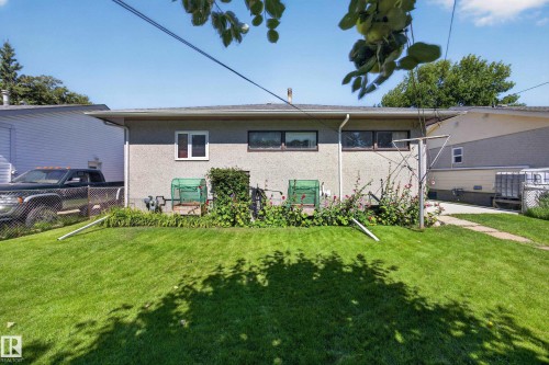 Expansive lawn with established garden beds and a concrete pathway leading to a chain-link fence - 5207 48 Avenue, Leduc, AB - Outdoor