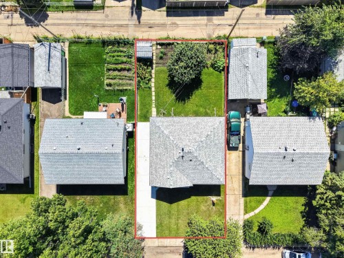 Manicured lawn surrounding the property, mature trees on property, paved driveway, detached garage with shingle roof, additional paved parking area - 5207 48 Avenue, Leduc, AB - Outdoor
