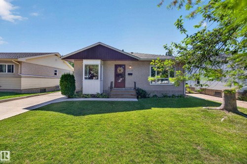 Stucco exterior with a bay window, asphalt shingle roof, concrete driveway, and established front lawn - 5207 48 Avenue, Leduc, AB - Outdoor