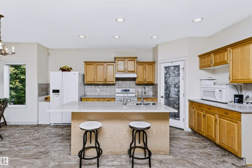 Kitchen featuring a large island with countertop seating, recessed lighting, wood cabinetry, and tiled flooring - 1720 Robertson Place Sw, Edmonton, AB - Indoor Photo Showing Kitchen