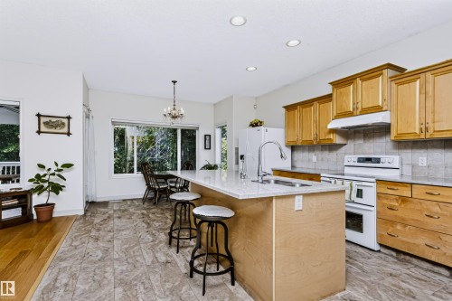 Kitchen featuring wood-finish cabinetry, light-toned countertops, a stainless steel sink, and recessed lighting - 1720 Robertson Place Sw, Edmonton, AB - Indoor Photo Showing Kitchen With Double Sink