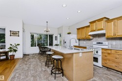 Kitchen featuring wood-finish cabinetry, light-toned countertops, a stainless steel sink, and recessed lighting - 