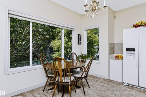 Expansive window with white trim, light-colored tile flooring, and a chandelier lighting fixture - 1720 Robertson Place Sw, Edmonton, AB - Indoor Photo Showing Dining Room