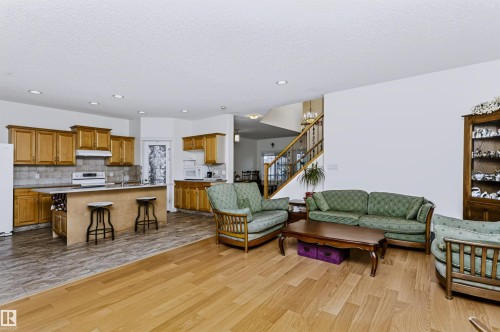 Open-concept living area with wood-finish flooring, recessed lighting, and a prominent staircase with wood railings - 1720 Robertson Place Sw, Edmonton, AB - Indoor Photo Showing Other Room