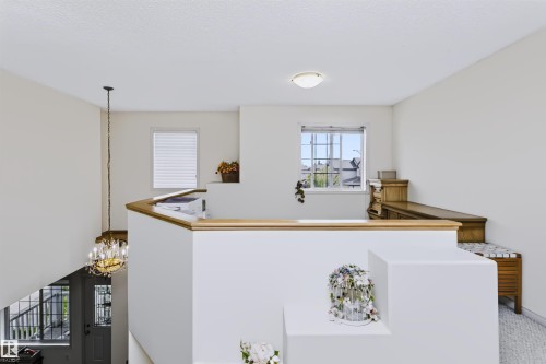 Upper-level landing with wood-finish railing, a window with grid detailing, and a flush-mount ceiling light - 1720 Robertson Place Sw, Edmonton, AB - Indoor Photo Showing Other Room