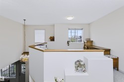 Upper-level landing with wood-finish railing, a window with grid detailing, and a flush-mount ceiling light - 