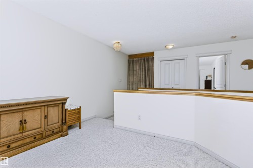 White carpeting throughout with a white wall divider and wood-finish railing - 1720 Robertson Place Sw, Edmonton, AB - Indoor Photo Showing Other Room
