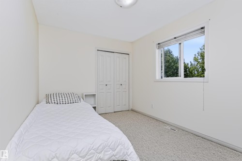 Neutral wall color, light-toned carpeting, window with natural light, and a built-in closet with bifold doors - 1720 Robertson Place Sw, Edmonton, AB - Indoor Photo Showing Bedroom