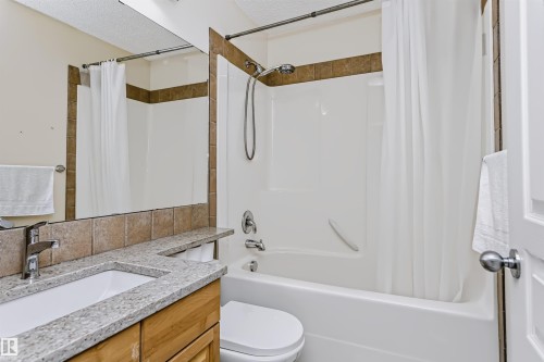 Integrated vanity with a rectangular sink, speckled countertop, and wood-finish cabinetry - 1720 Robertson Place Sw, Edmonton, AB - Indoor Photo Showing Bathroom