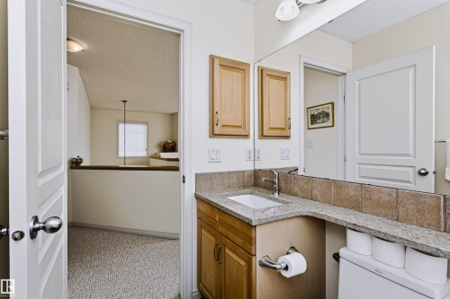Vanity with a granite countertop, undermount sink, and wood-finish cabinetry - 1720 Robertson Place Sw, Edmonton, AB - Indoor Photo Showing Bathroom