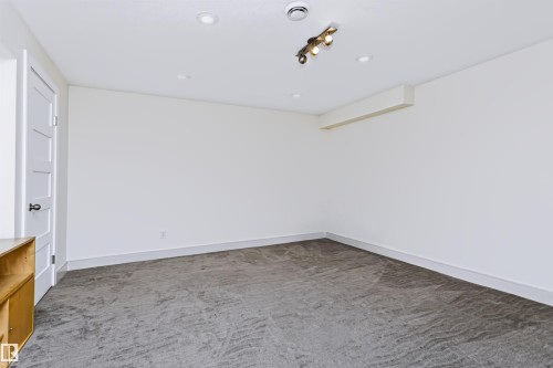 Recessed ceiling lighting, track lighting fixture, white interior door with contemporary hardware, light gray carpeting, and white wall finishes - 1720 Robertson Place Sw, Edmonton, AB - Indoor Photo Showing Other Room