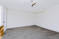 Recessed ceiling lighting, track lighting fixture, white interior door with contemporary hardware, light gray carpeting, and white wall finishes - 