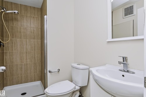 Walk-in shower with tiled surround and glass enclosure - 1720 Robertson Place Sw, Edmonton, AB - Indoor Photo Showing Bathroom