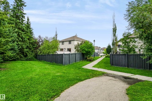 Expansive green space with mature trees, paved pathway, and privacy fencing - 1720 Robertson Place Sw, Edmonton, AB - Outdoor With Backyard