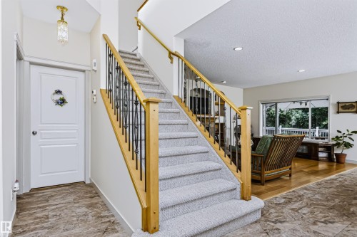 Carpeted staircase with wood newel posts and wrought iron balusters, recessed ceiling lighting, wood-finish flooring, and a glass-paneled exterior door - 1720 Robertson Place Sw, Edmonton, AB - Indoor Photo Showing Other Room