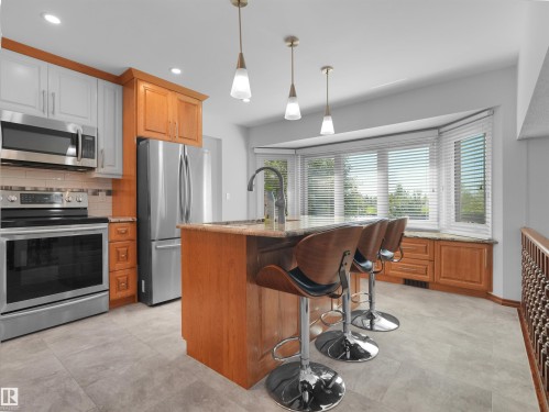 Kitchen featuring a bay window, stainless steel appliances, an island with seating, pendant lighting, and tile flooring - 7357 18 Avenue Nw, Edmonton, AB - Indoor Photo Showing Kitchen With Upgraded Kitchen