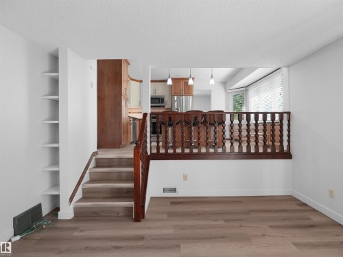 Wood-finish flooring, built-in shelving, wood staircase, and an open-concept kitchen with pendant lighting - 7357 18 Avenue Nw, Edmonton, AB - Indoor Photo Showing Other Room