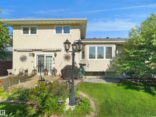 Stucco exterior with multiple windows and a sliding glass door - 7357 18 Avenue Nw, Edmonton, AB - Outdoor