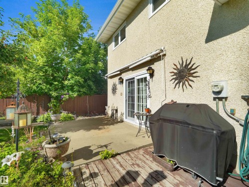 Stucco exterior with sliding glass patio doors, a concrete patio, and a wood deck - 7357 18 Avenue Nw, Edmonton, AB - Outdoor With Exterior