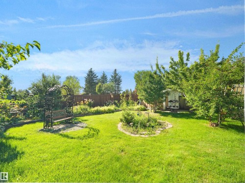 Expansive manicured lawn with mature landscaping, circular garden bed plantings, and wooden arbor structures - 7357 18 Avenue Nw, Edmonton, AB - Outdoor With View