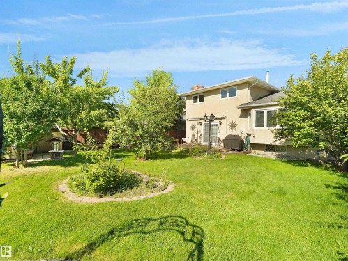 Expansive green lawn with mature trees and a dedicated garden bed - 7357 18 Avenue Nw, Edmonton, AB - Outdoor