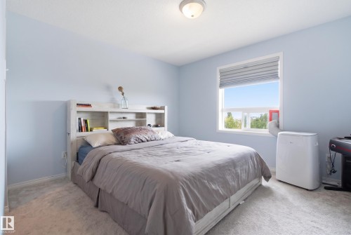 Light blue wall paint and light-toned carpet flooring - #2415 9357 Simpson Dr Nw, Edmonton, AB - Indoor Photo Showing Bedroom