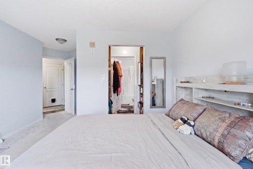 Carpeted flooring, light-colored walls, and a built-in headboard - #2415 9357 Simpson Dr Nw, Edmonton, AB - Indoor Photo Showing Bedroom