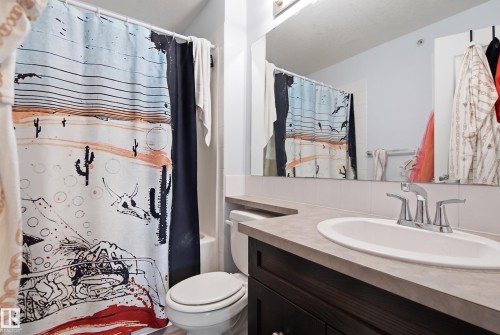 Vanity with a built-in sink, chrome faucet, and dark wood-finish cabinetry - #2415 9357 Simpson Dr Nw, Edmonton, AB - Indoor Photo Showing Bathroom