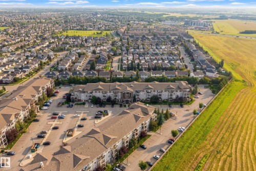 Low-rise residential buildings with ample surface parking, surrounded by established suburban housing, cultivated agricultural fields, and natural green spaces - #2415 9357 Simpson Dr Nw, Edmonton, AB - Outdoor With View