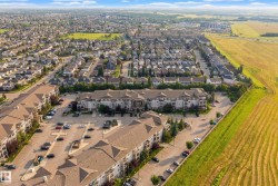 Low-rise residential buildings with ample surface parking, surrounded by established suburban housing, cultivated agricultural fields, and natural green spaces - 
