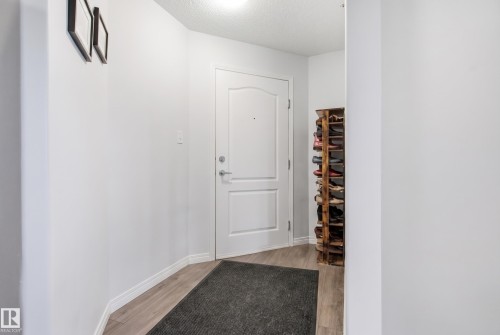 Entryway featuring a white paneled door, light wood-finish flooring, and neutral wall tones - #2415 9357 Simpson Dr Nw, Edmonton, AB - Indoor Photo Showing Other Room
