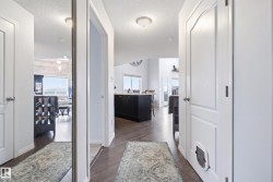 Hallway featuring wood-finish flooring, white paneled doors, and a full-length mirrored closet door - 