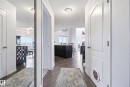 Hallway featuring wood-finish flooring, white paneled doors, and a full-length mirrored closet door - #2415 9357 Simpson Dr Nw, Edmonton, AB  - Indoor Photo Showing Other Room 