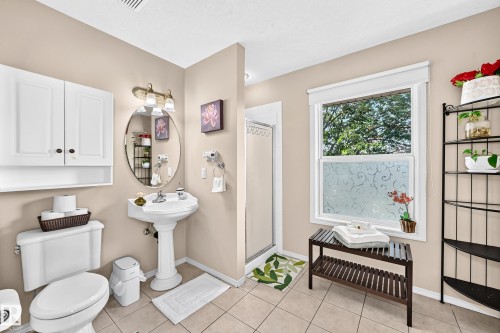 Pedestal sink, wall-mounted vanity light, white cabinetry, frosted window, and tiled flooring - 4210 37 Avenue Nw, Edmonton, AB - Indoor Photo Showing Bathroom