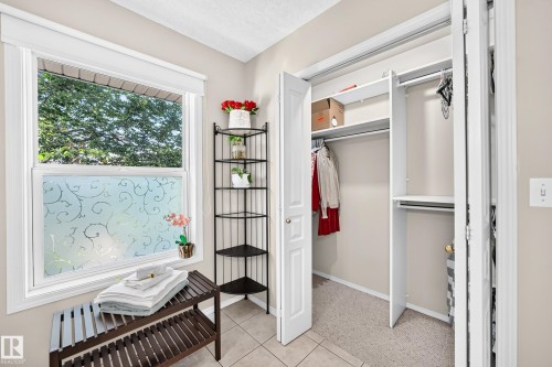 Window with decorative privacy film, light-colored wall paint, tiled flooring, and a built-in closet with shelving and hanging rods - 4210 37 Avenue Nw, Edmonton, AB - Indoor