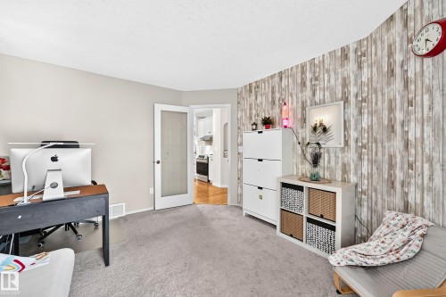 Carpeted room with a frosted glass door, light gray wall, and a rustic wood-finish accent wall - 4210 37 Avenue Nw, Edmonton, AB - Indoor