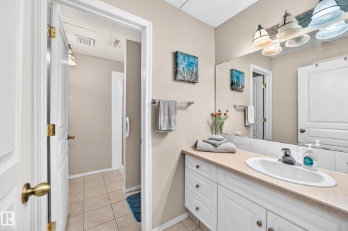 Full-width vanity mirror, white cabinetry, integrated sink, and durable countertop - 4210 37 Avenue Nw, Edmonton, AB - Indoor Photo Showing Bathroom