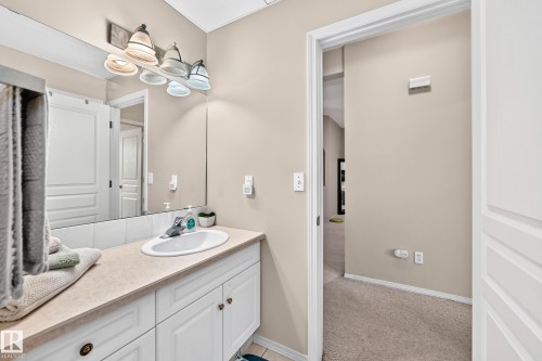 Vanity featuring a single basin sink with chrome faucet, light-toned countertop, and white cabinetry - 4210 37 Avenue Nw, Edmonton, AB - Indoor Photo Showing Bathroom
