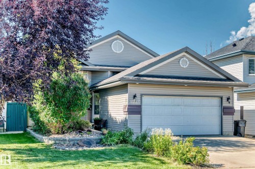 Two-story residence with siding exterior, attached garage, and a landscaped front yard featuring mature trees and shrubs - 4210 37 Avenue Nw, Edmonton, AB - Outdoor
