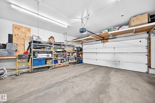 Concrete flooring, overhead lighting, overhead garage door, built-in shelving, mounted garage door opener - 4210 37 Avenue Nw, Edmonton, AB - Indoor Photo Showing Garage
