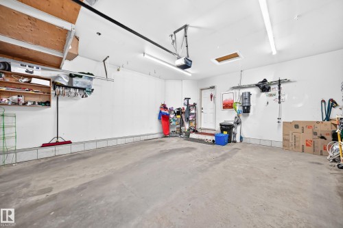 Spacious garage with concrete flooring, overhead wood-finish storage, and white walls - 4210 37 Avenue Nw, Edmonton, AB - Indoor Photo Showing Garage