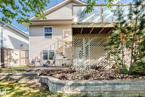 Multi-level retaining wall landscaping, spiral staircase, upper-level balcony, lattice privacy screening, and horizontal siding - 4210 37 Avenue Nw, Edmonton, AB - Outdoor With Deck Patio Veranda