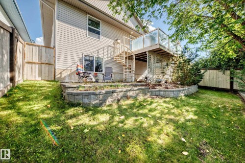 Rear exterior featuring siding, a second-story deck with glass railing, spiral staircase, and a retaining wall - 4210 37 Avenue Nw, Edmonton, AB - Outdoor With Deck Patio Veranda