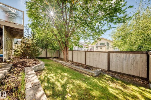 Fenced yard featuring a mature tree, stone retaining walls, and a manicured lawn - 4210 37 Avenue Nw, Edmonton, AB - Outdoor