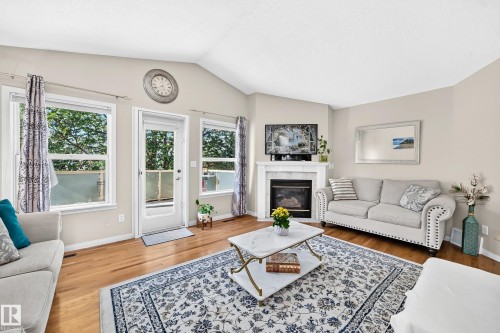 Vaulted ceiling living area with hardwood-finish flooring, a white mantel fireplace, and a glass-paneled exterior door - 4210 37 Avenue Nw, Edmonton, AB - Indoor Photo Showing Living Room With Fireplace