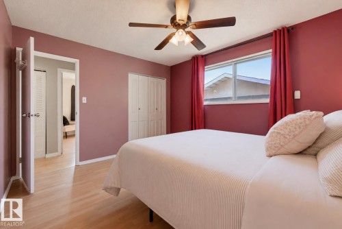 Wood-finish flooring, ceiling fan with integrated lighting, window with a white frame, and bi-fold closet doors - 6768 39 Avenue Nw, Edmonton, AB - Indoor Photo Showing Bedroom