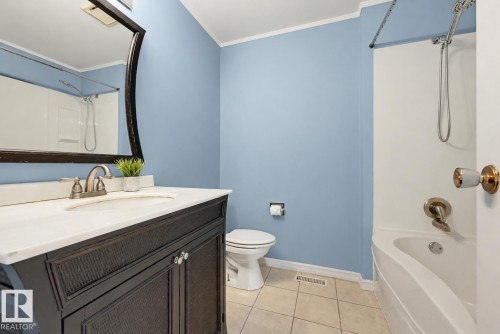 White countertop vanity with a dark wood-finish cabinet, brushed nickel faucet, and a large wall mirror - 6768 39 Avenue Nw, Edmonton, AB - Indoor Photo Showing Bathroom